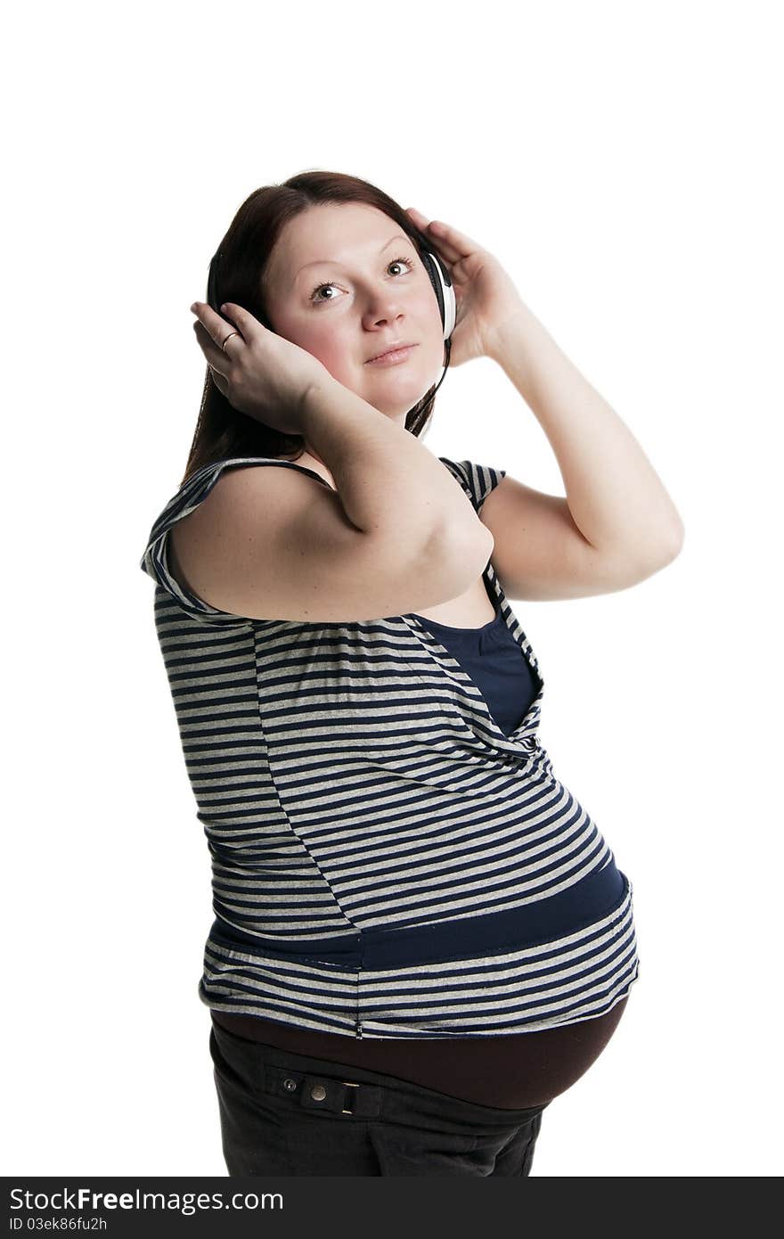 Beautiful pregnant woman listens to music, isolated on white