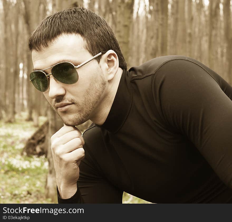 Young man in black clothes and sunglasses closeup portrait