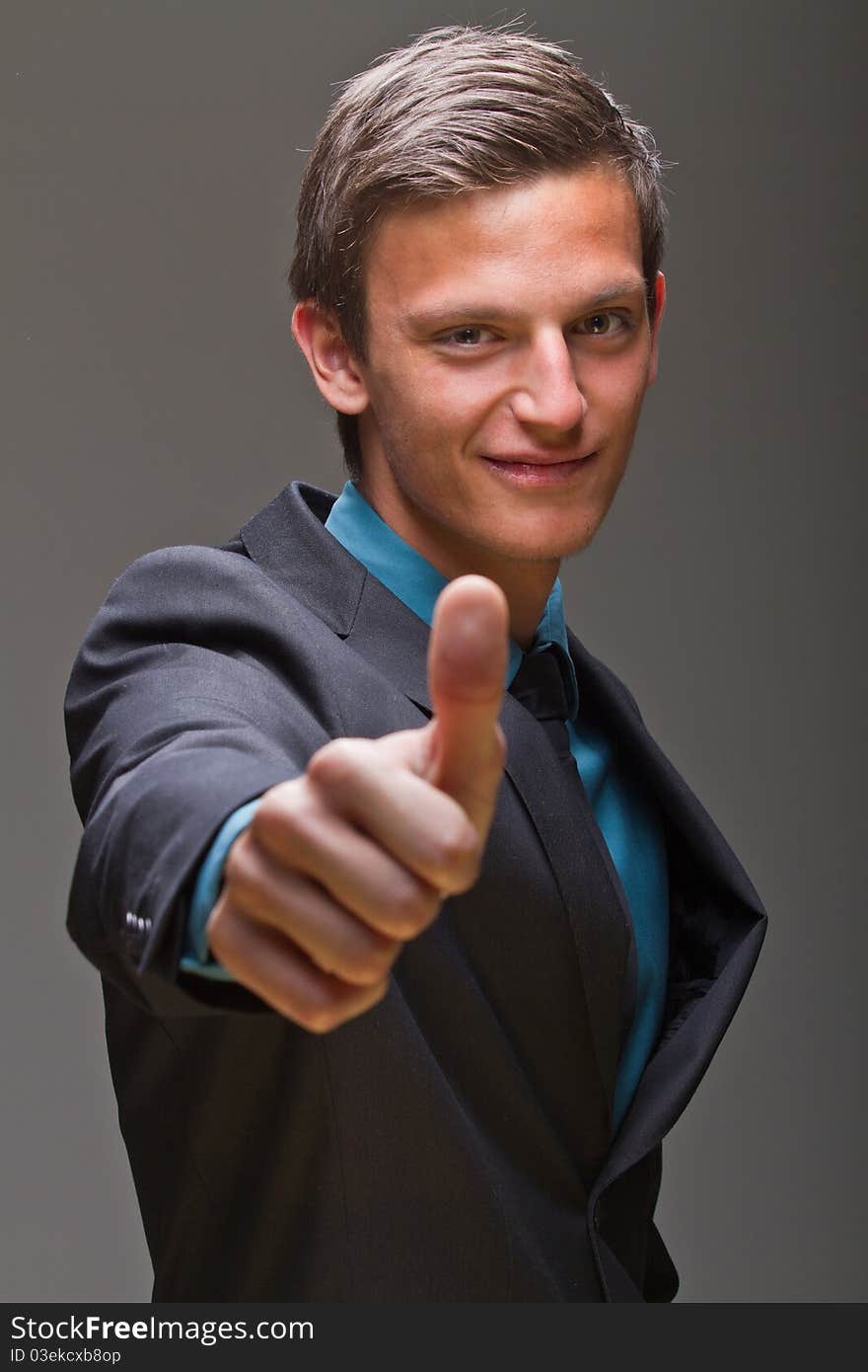 Young businessman showing a thumbs up sign. Expressing positive attitude. Young businessman showing a thumbs up sign. Expressing positive attitude.