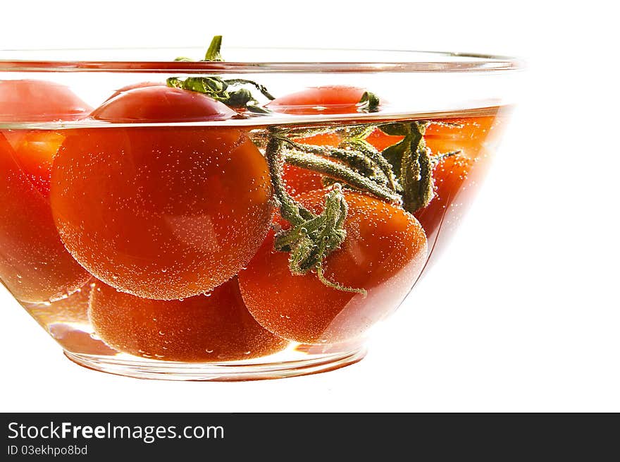 Red tomatoes in a plate with water on the white isolated background