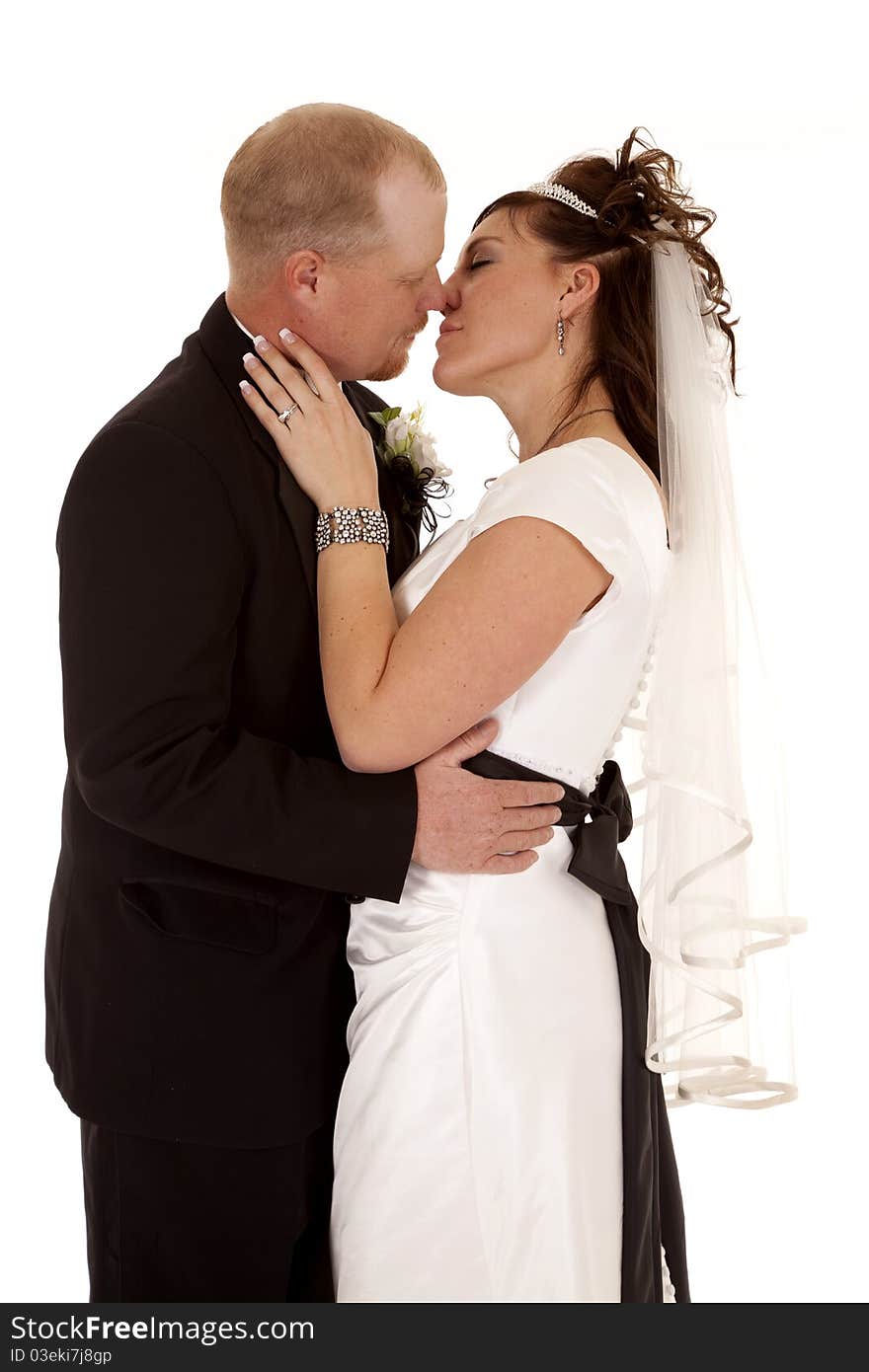 A bride and groom holding each other and almost kissing on their lips.