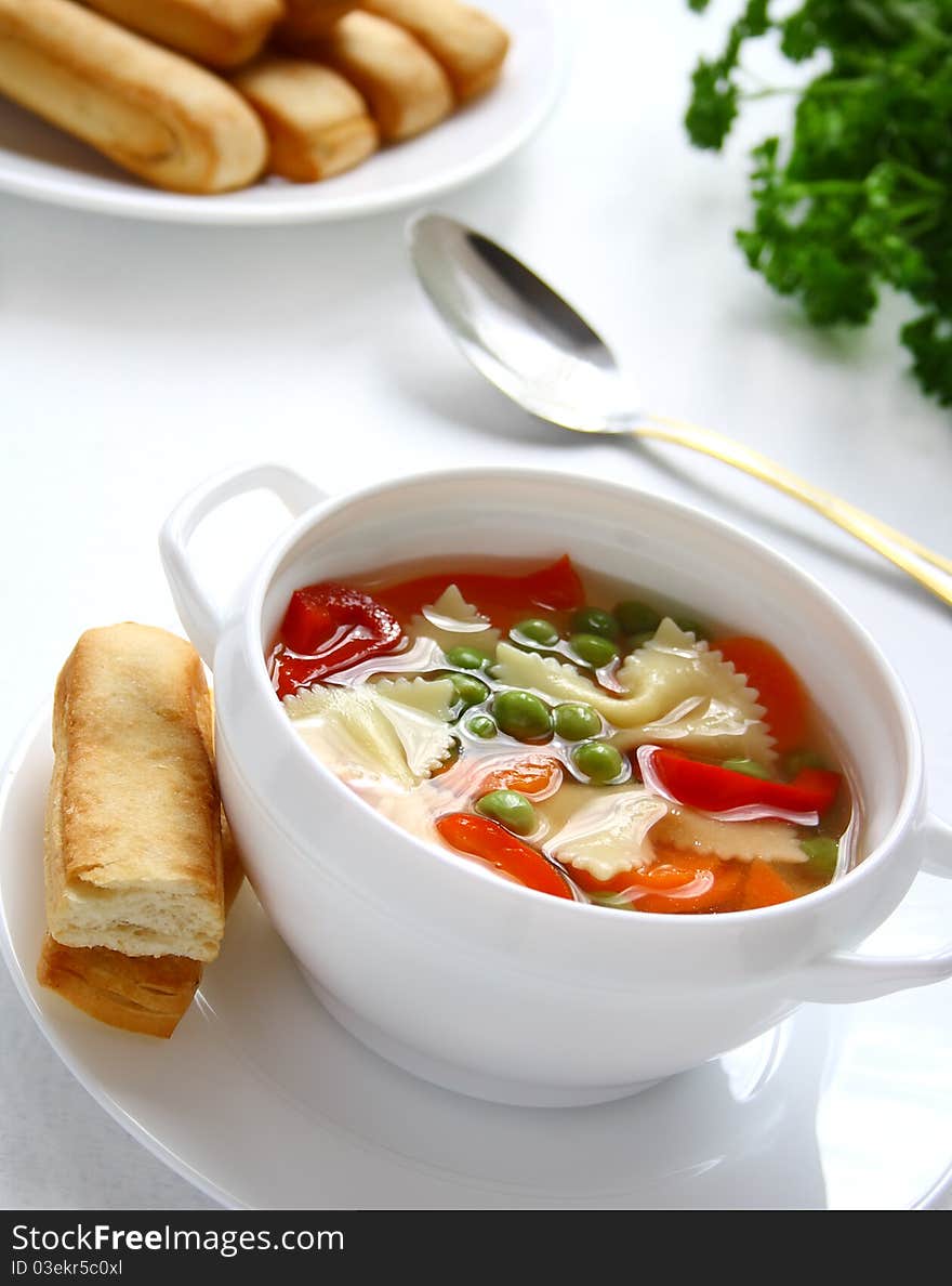 A bowl of vegetarian vegetable soup with farfalia on the table. A bowl of vegetarian vegetable soup with farfalia on the table.