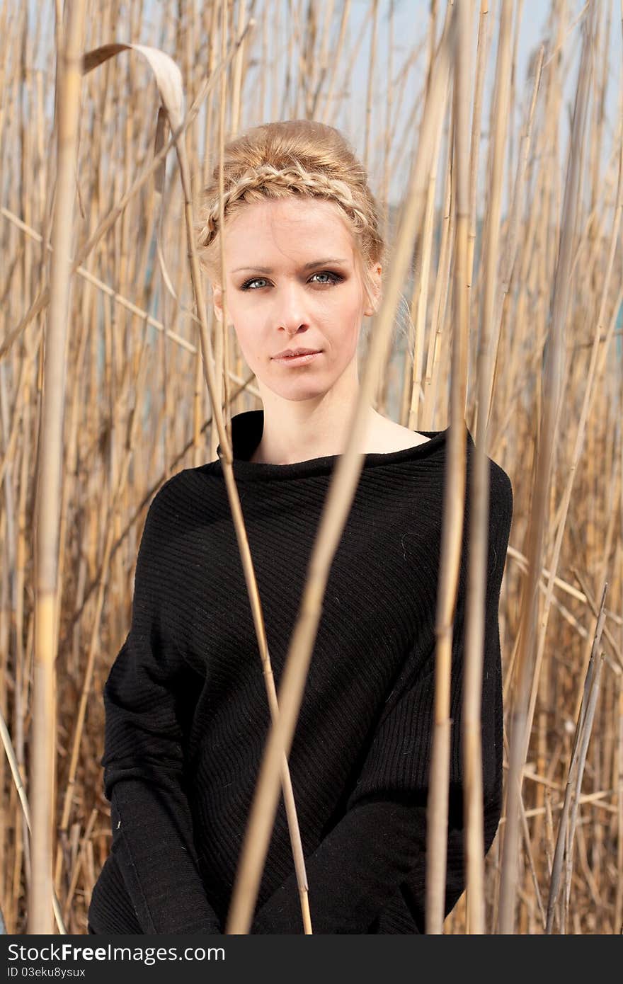 Outdoor portrait of young beautiful blond slim girl in the reed zone of the park. Outdoor portrait of young beautiful blond slim girl in the reed zone of the park