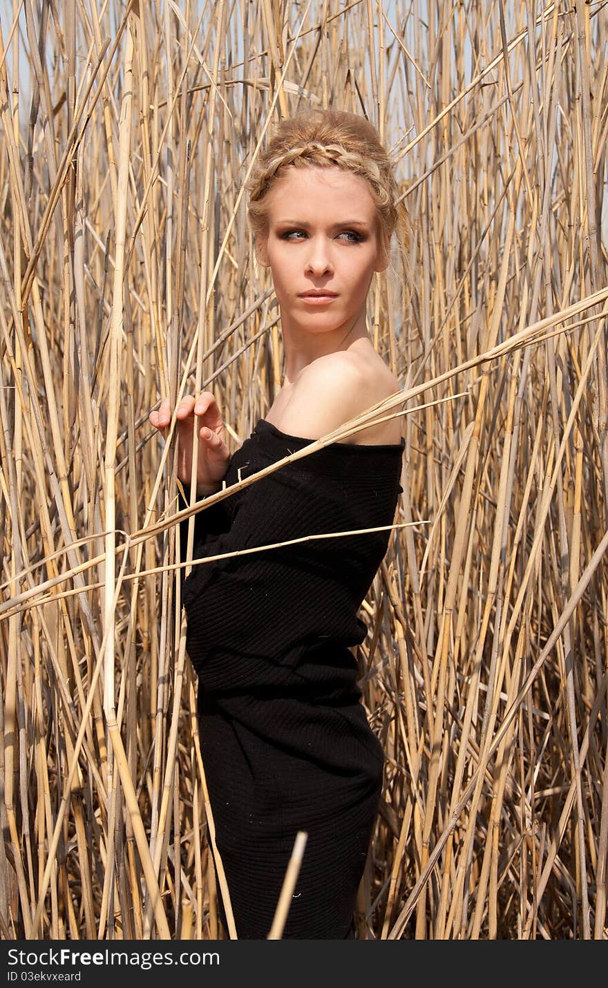 Outdoor portrait of young beautiful blond slim girl in the reed zone of the park. Outdoor portrait of young beautiful blond slim girl in the reed zone of the park