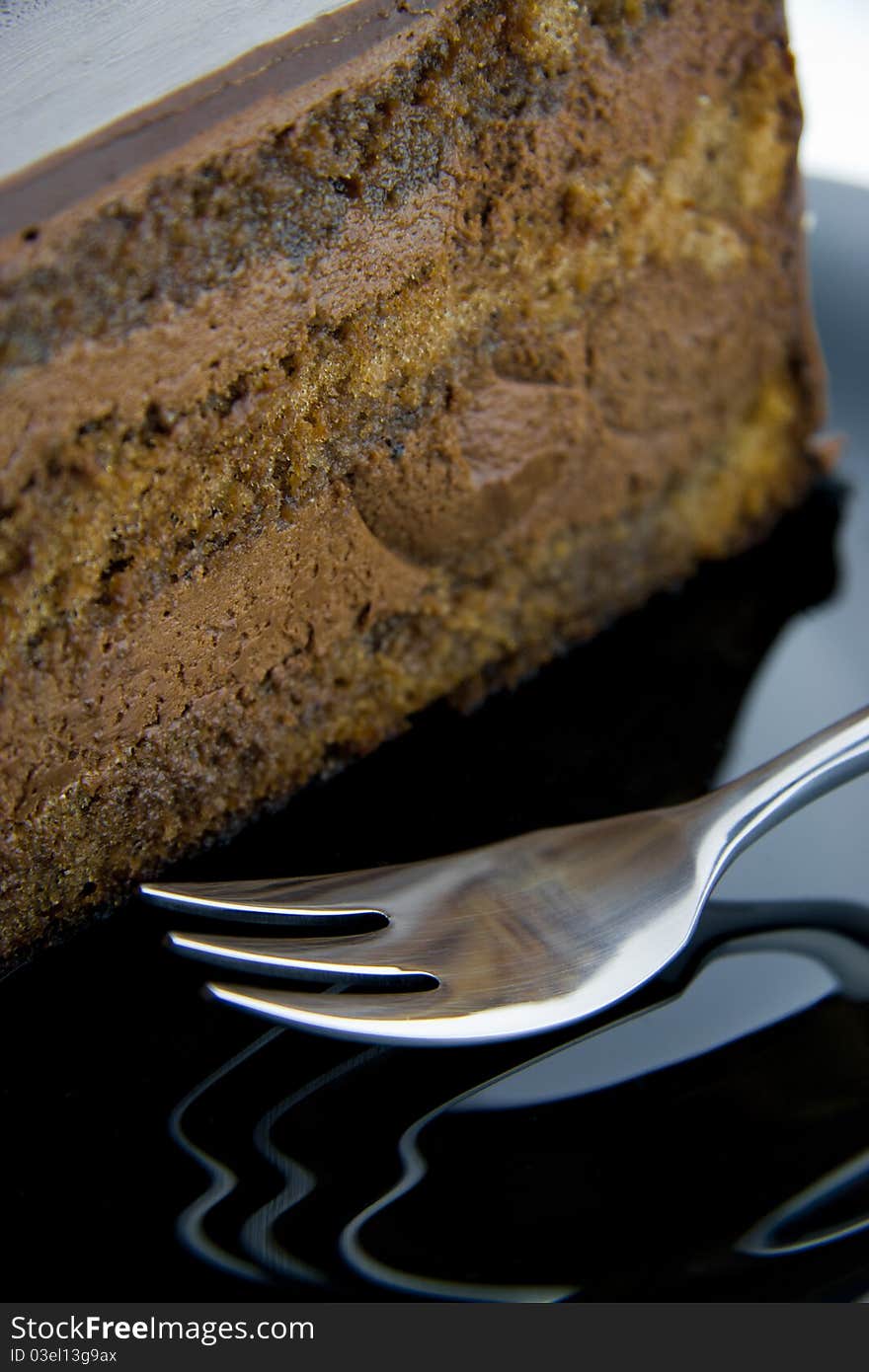 Slice of chocolate cake on a black plate with fork. Slice of chocolate cake on a black plate with fork