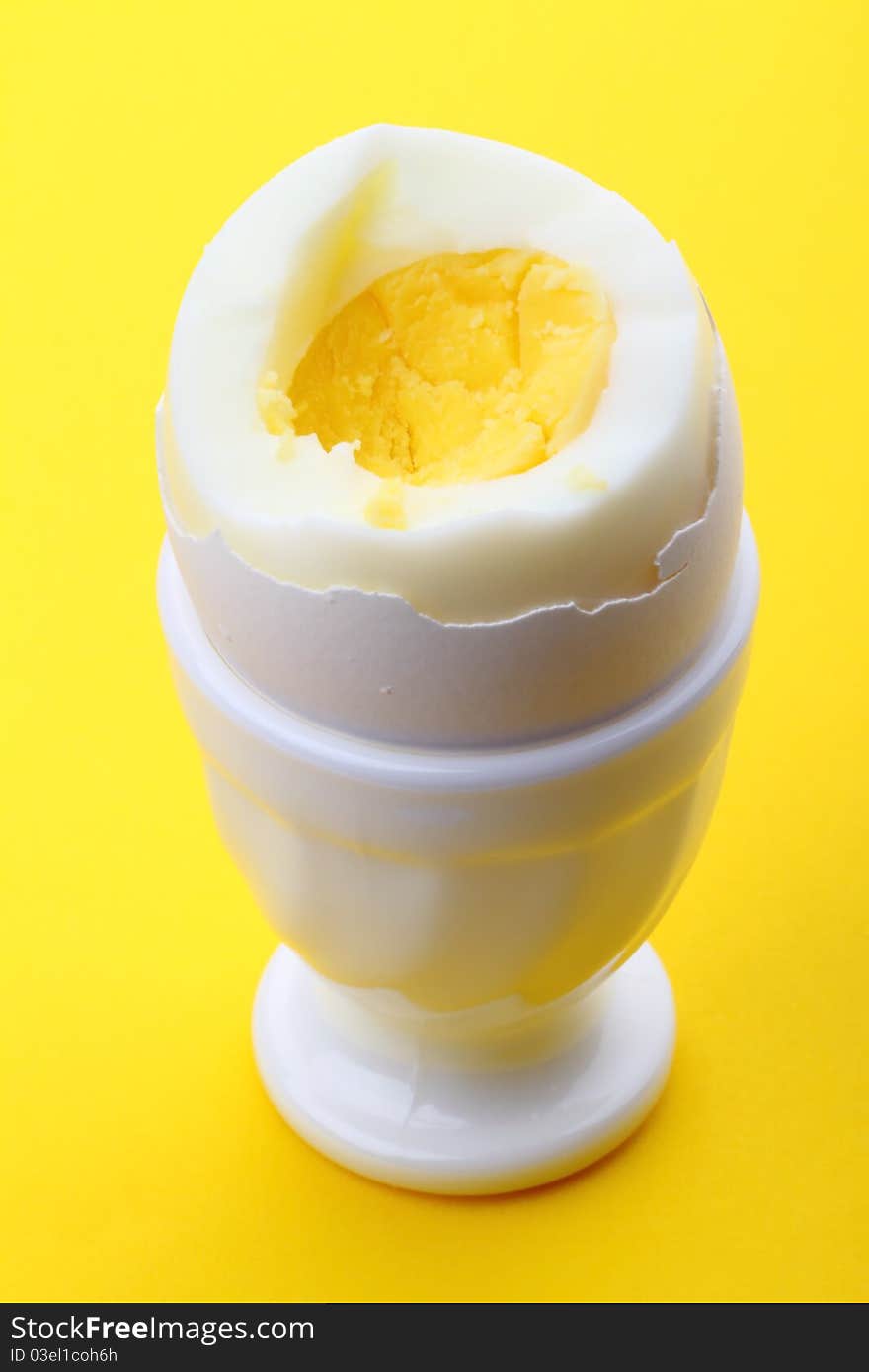 Single egg in cup on yellow background