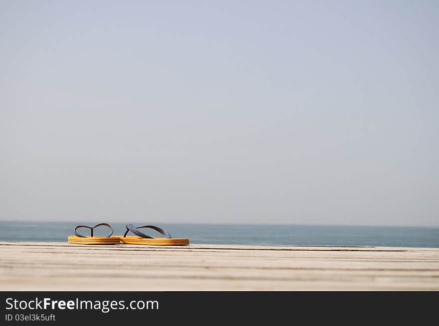 Orange Flip-flops on the wood panels and ocean view