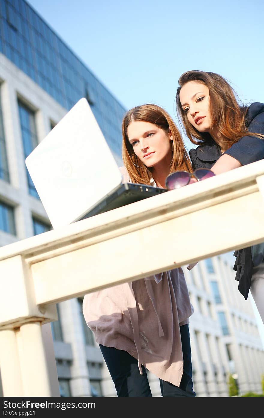 Two young girls outside with laptop