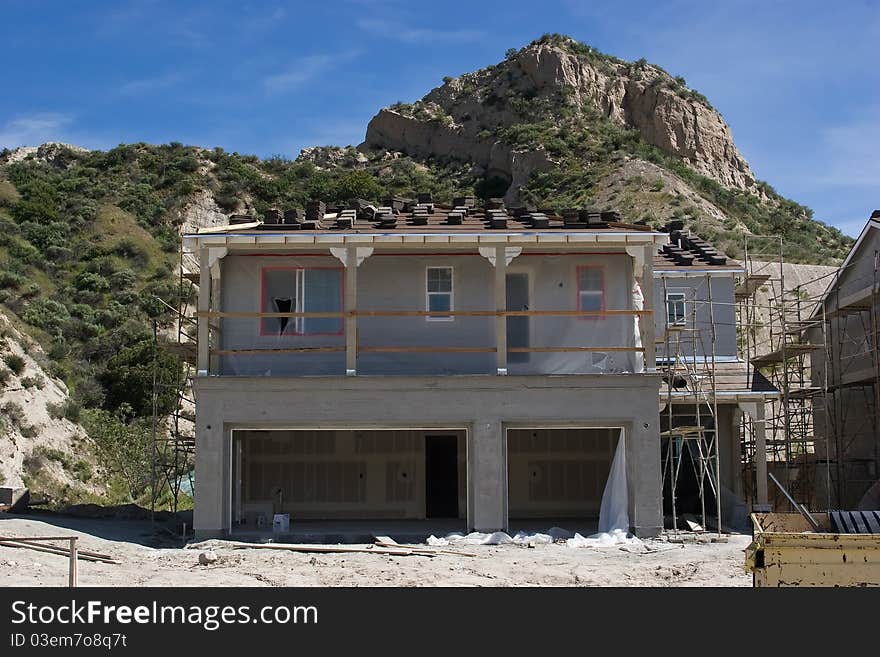 A new house is under construction with hillside behind it. A new house is under construction with hillside behind it.