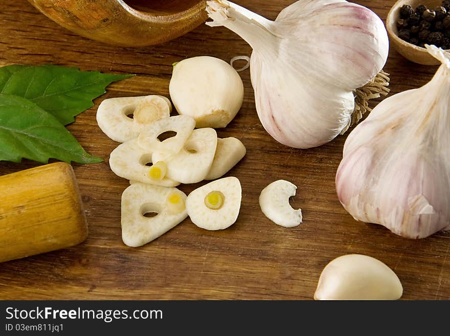 Garlic, spoon and pepper on wood