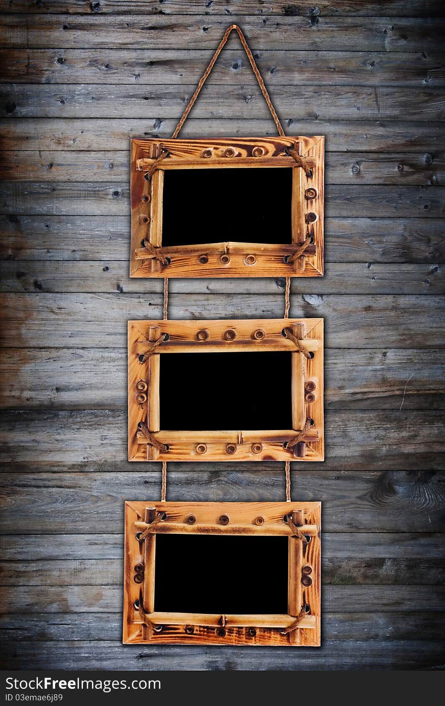 Three bamboo frames on dark wooden wall with artistic shadows added