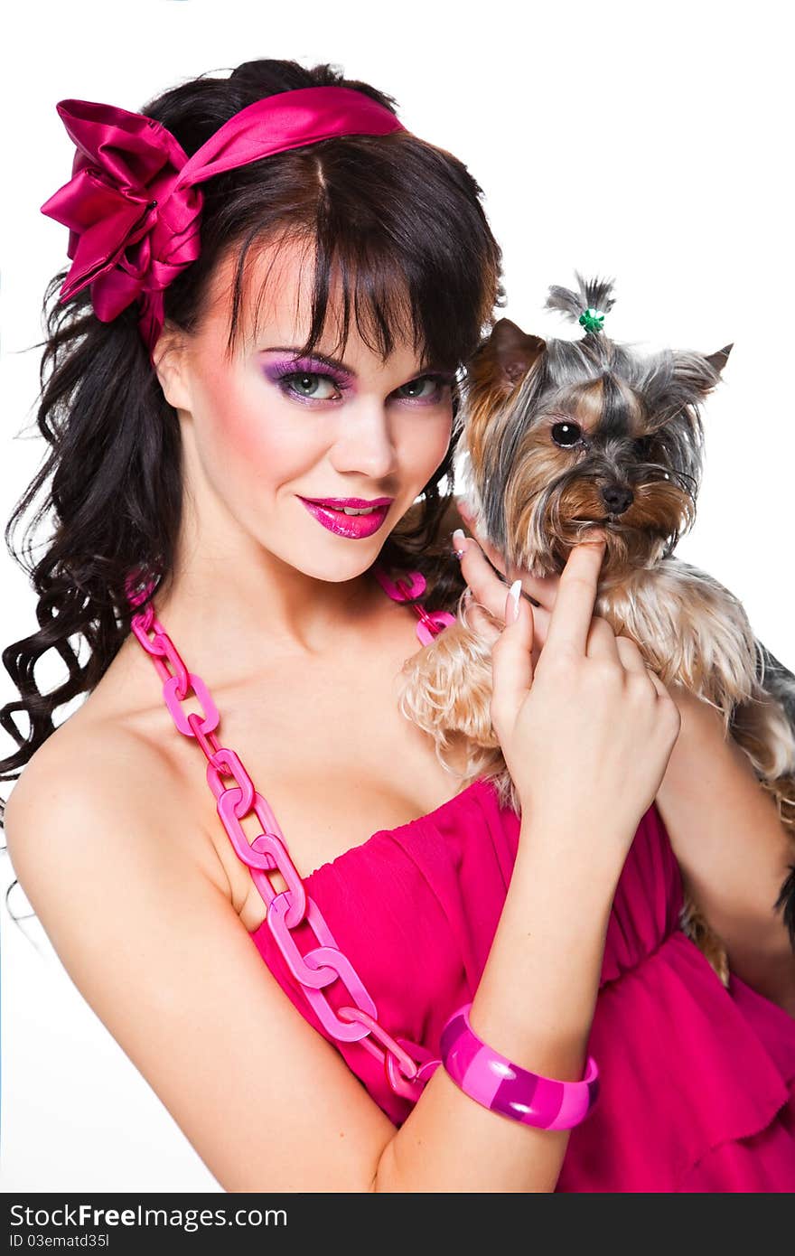 Portrait of beautiful girl with dark long curly hair and vibrant make-up wearing pink satiny ribbon holding small dog on white background. Portrait of beautiful girl with dark long curly hair and vibrant make-up wearing pink satiny ribbon holding small dog on white background