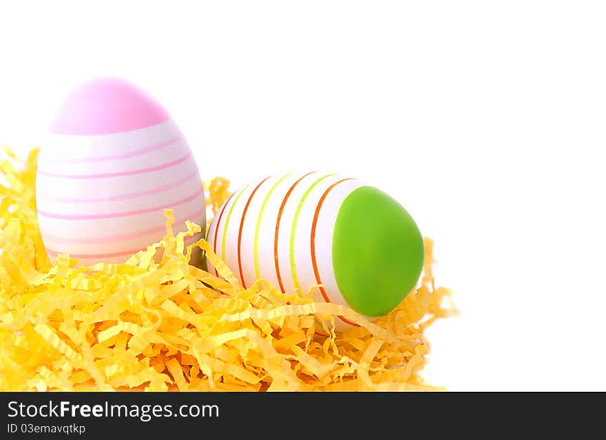 Two easter eggs in yellow nest on white background