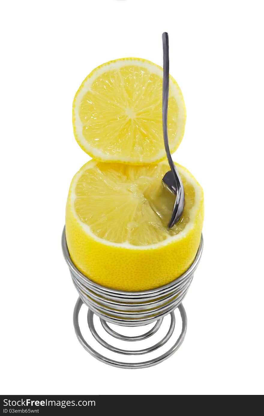 Bright lemon in the metal spiral eggcup with spoon on the white background. Bright lemon in the metal spiral eggcup with spoon on the white background