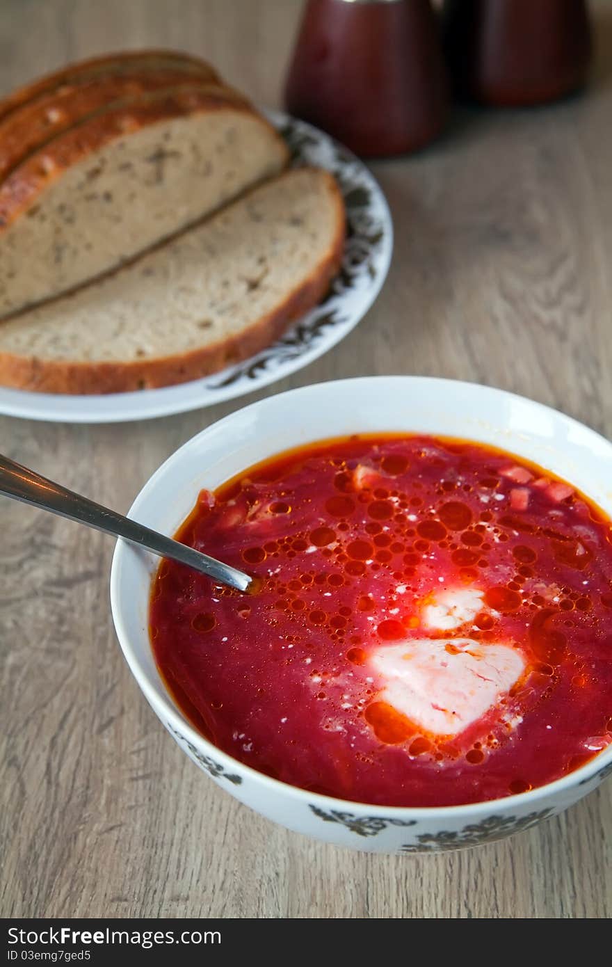 Traditional borscht with beet, meat, potatoes and sour cream, served with grey bread