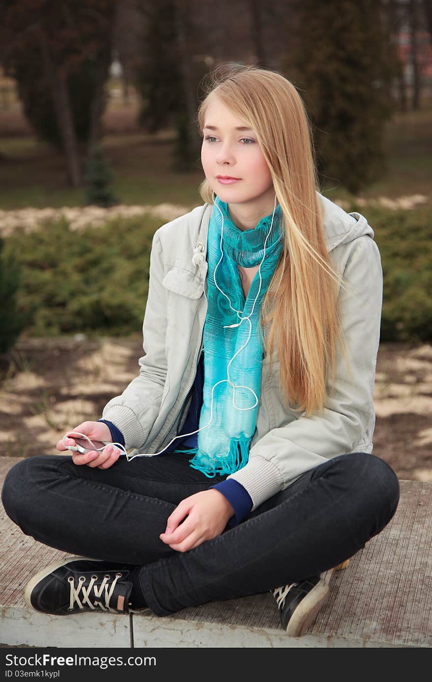 A young girl chilling to music outside. A young girl chilling to music outside