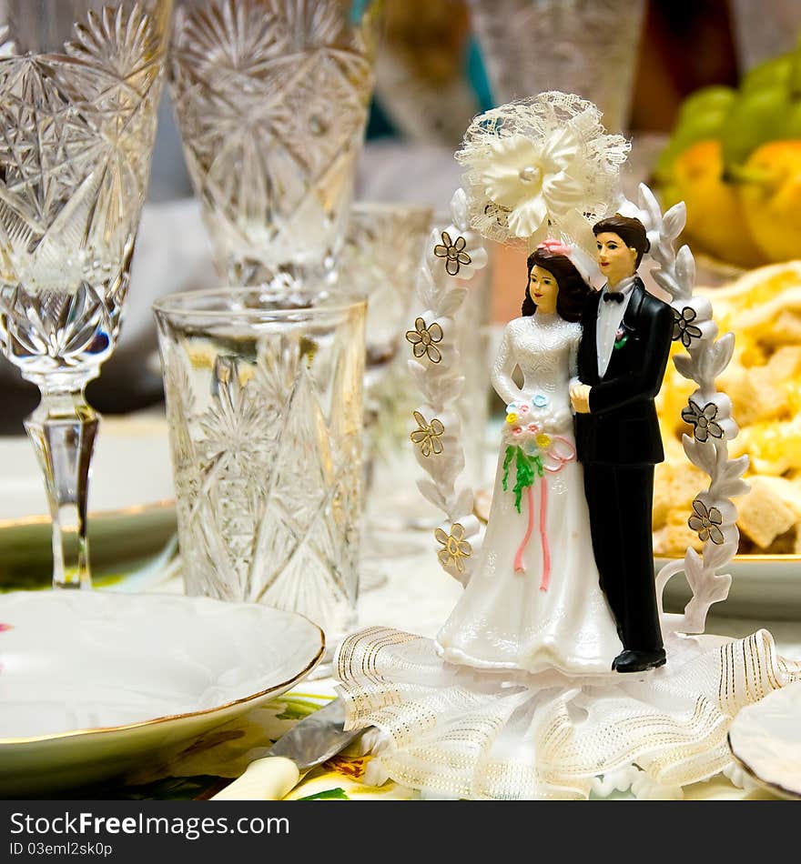 At the wedding table among the wine glasses there is a small figurine - figurine of the bride and groom