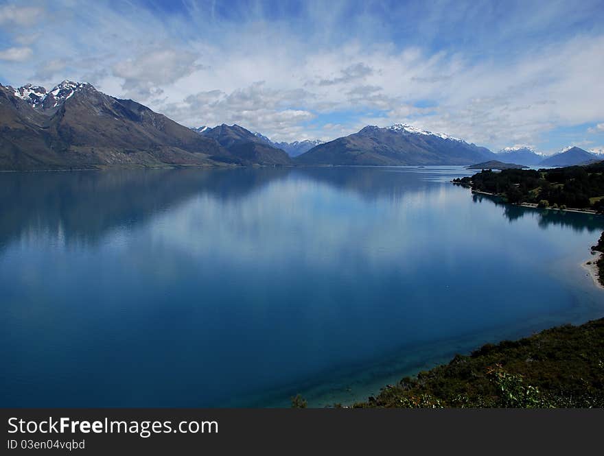 A beautiful reflection of the sky is created by a flat lake in Queenstown New Zealand