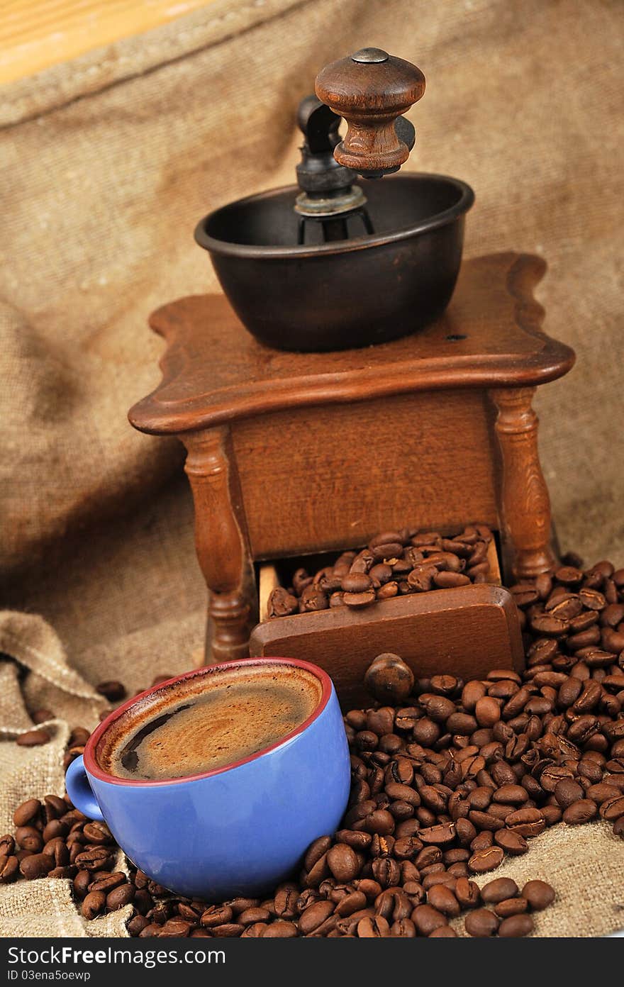 Vintage manual coffee grinder with coffee beans and cup