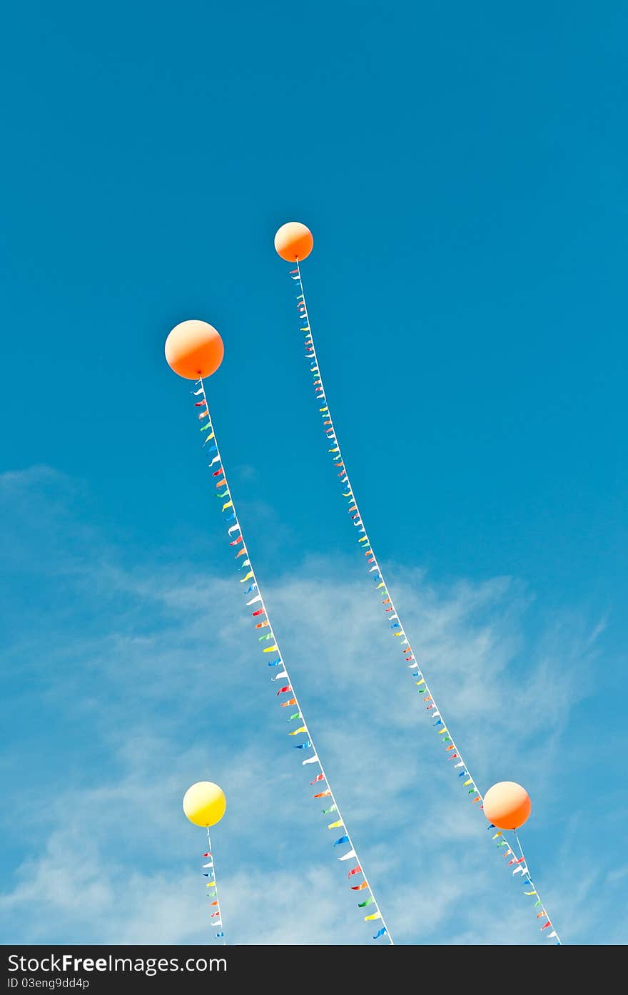 Colorful balloons and streamers wave in a blue sky with clouds. Colorful balloons and streamers wave in a blue sky with clouds.