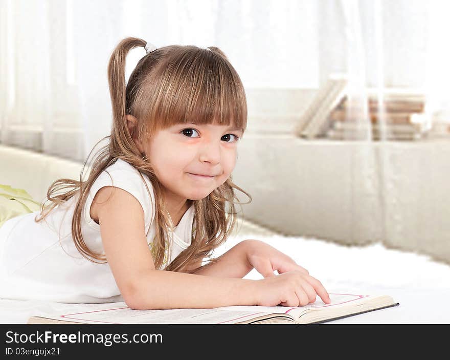 Lovely little girl, reading a book, on the bed. Lovely little girl, reading a book, on the bed