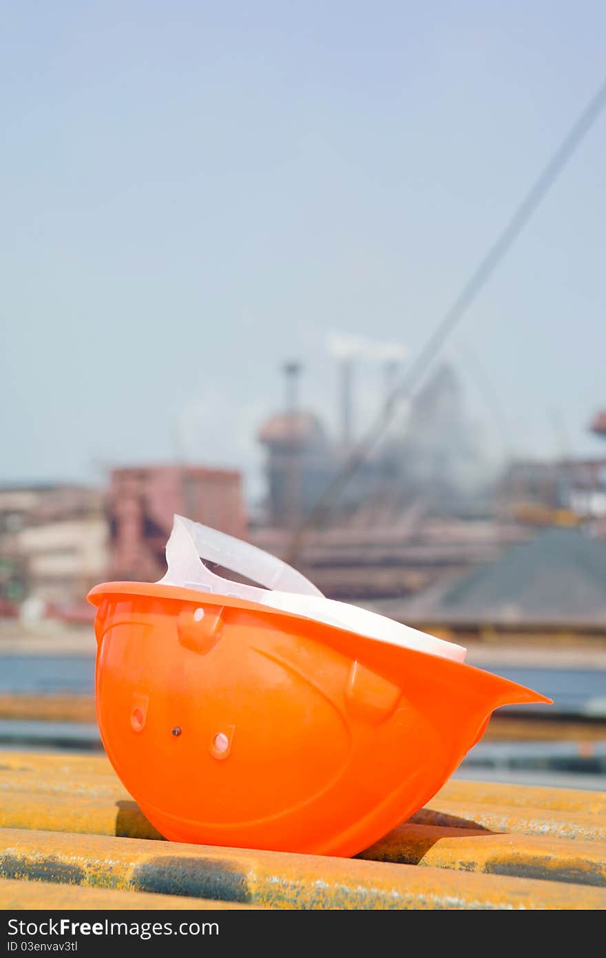 Hat working in the foreground and a metallurgical plant in the background