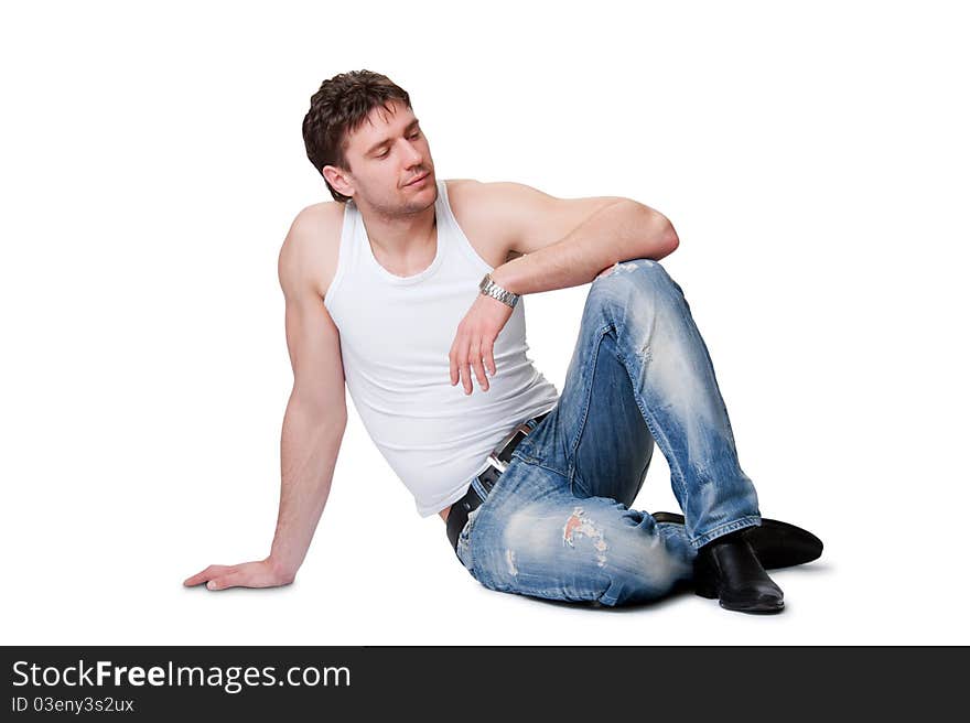 Young man in jeans sitting on an isolated background