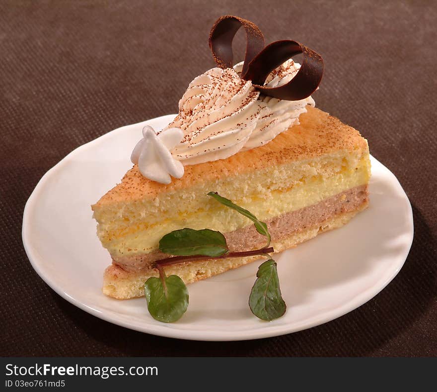 Share of the cake from layers of cream adorned with slices of cherry and sour sauce