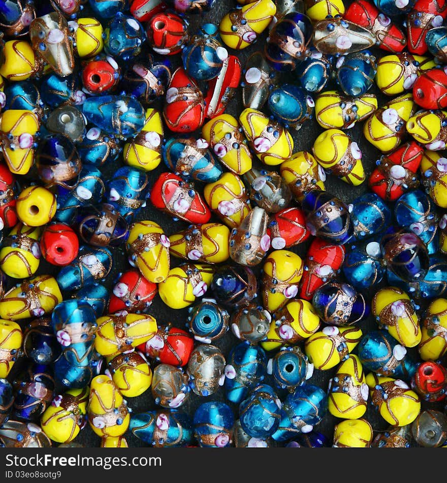 Glass and plastic bright red-yellow-blue costume jewellery on a street market table. Good for background. Glass and plastic bright red-yellow-blue costume jewellery on a street market table. Good for background.