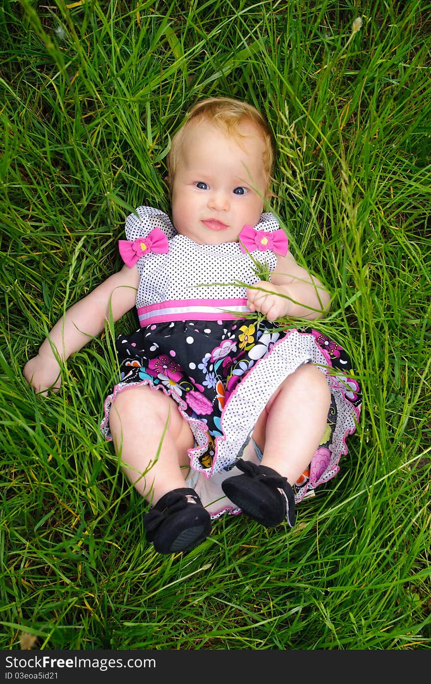 A beautiful little baby girl lying in the grass