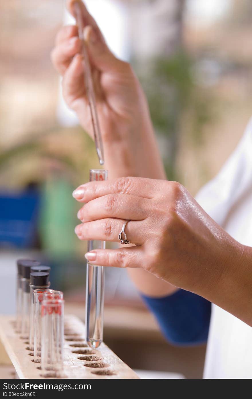 Woman pours a drop of liquid in a flask