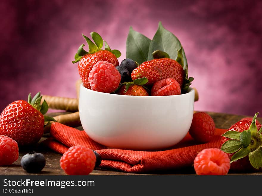 Photo of berries inside a white bowl on wooden table