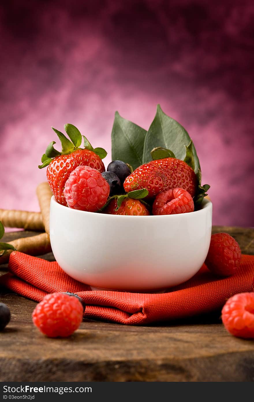 Photo of berries inside a white bowl on wooden table