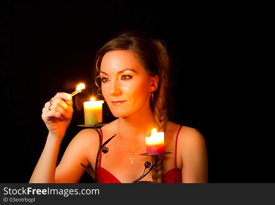 Girl lights a candle at an isolated black background. Girl lights a candle at an isolated black background