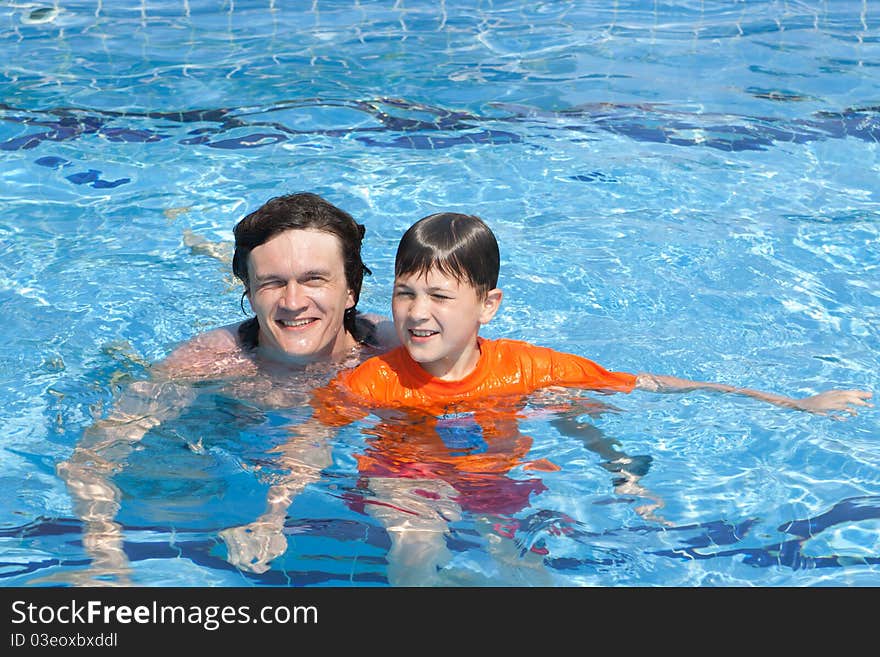 The father and the son swim in pool