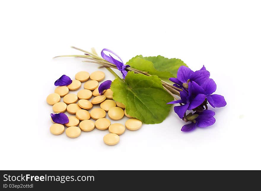 Herbal  pills and flowers on a white background