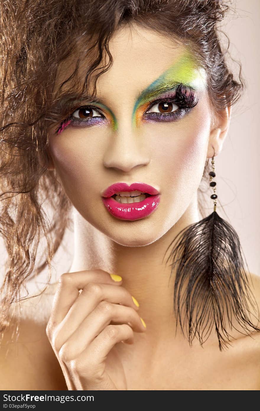 Beautiful young attracive female face with bright fashion multicolored make-up and beauty yellow manicure of fingernails. Beautiful young attracive female face with bright fashion multicolored make-up and beauty yellow manicure of fingernails