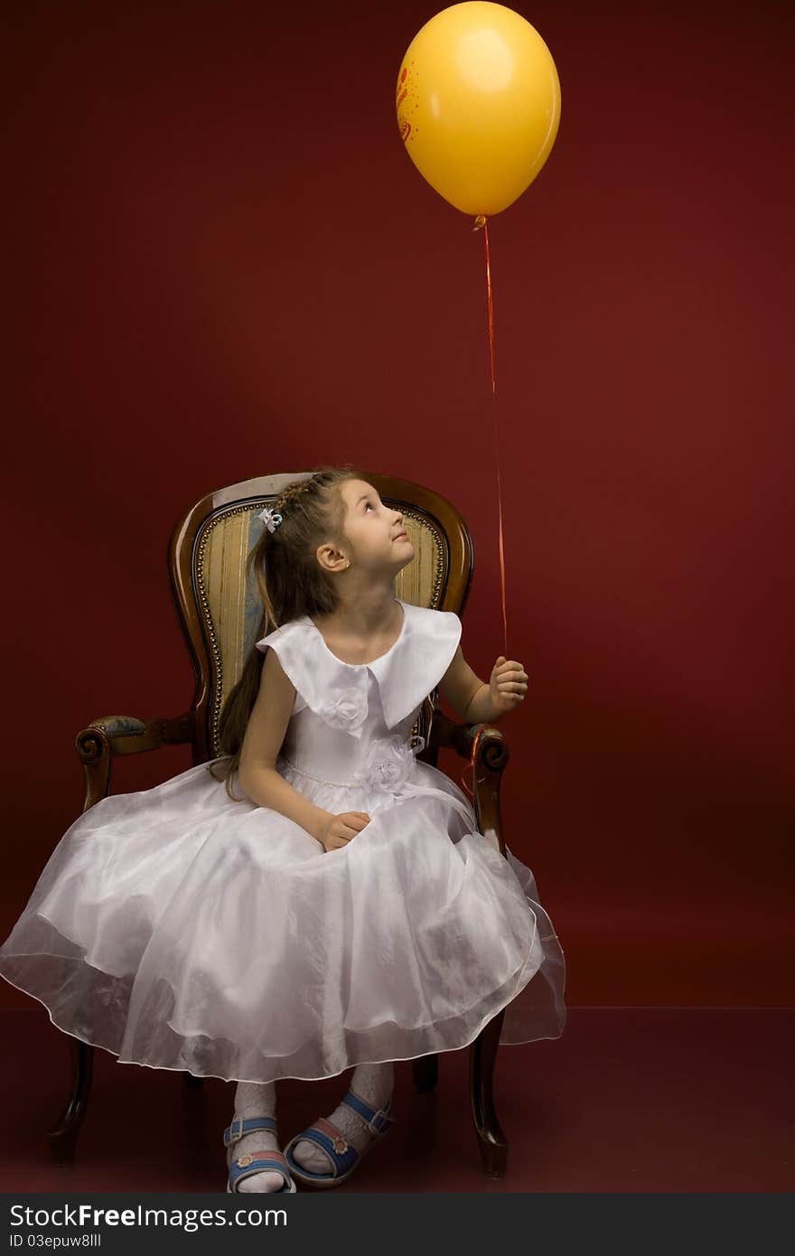 Studio portrait of a young pretty girl sitting on the armchair and with yellow balloon. Studio portrait of a young pretty girl sitting on the armchair and with yellow balloon