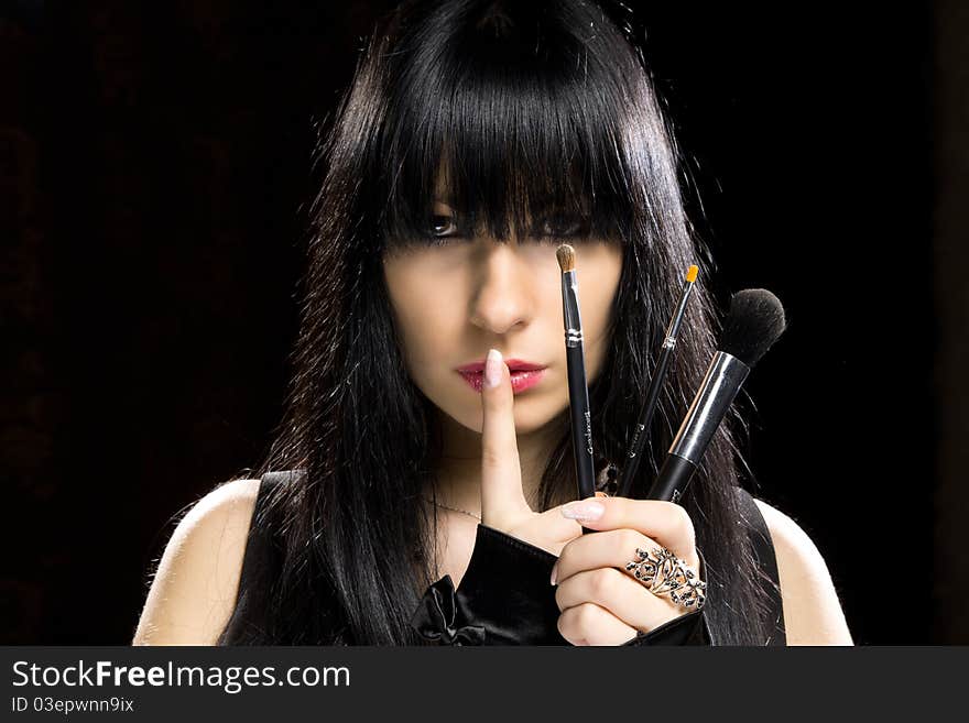 Close-up portrait of a young beautiful brunette girl with long hair and long nails holding brushes. Close-up portrait of a young beautiful brunette girl with long hair and long nails holding brushes