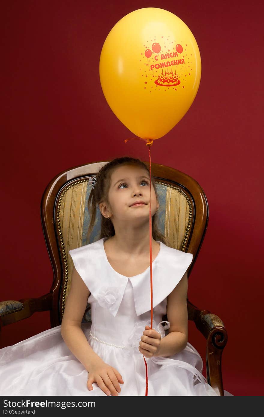 Studio portrait of a young pretty girl sitting on the armchair and with yellow balloon. Studio portrait of a young pretty girl sitting on the armchair and with yellow balloon