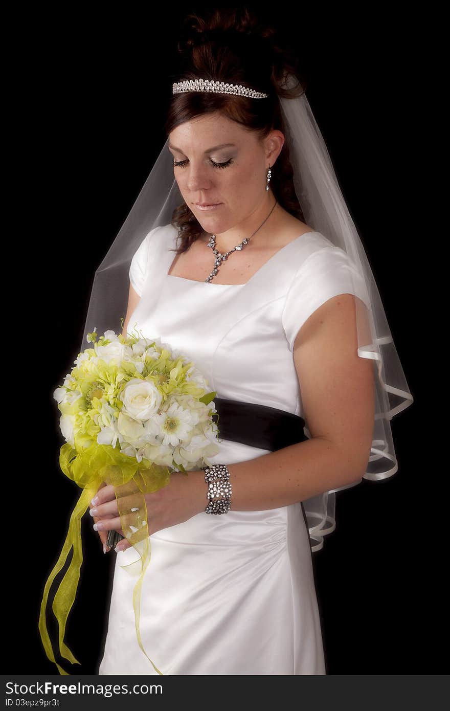 A bride on a black background looking down at her flowers. A bride on a black background looking down at her flowers.