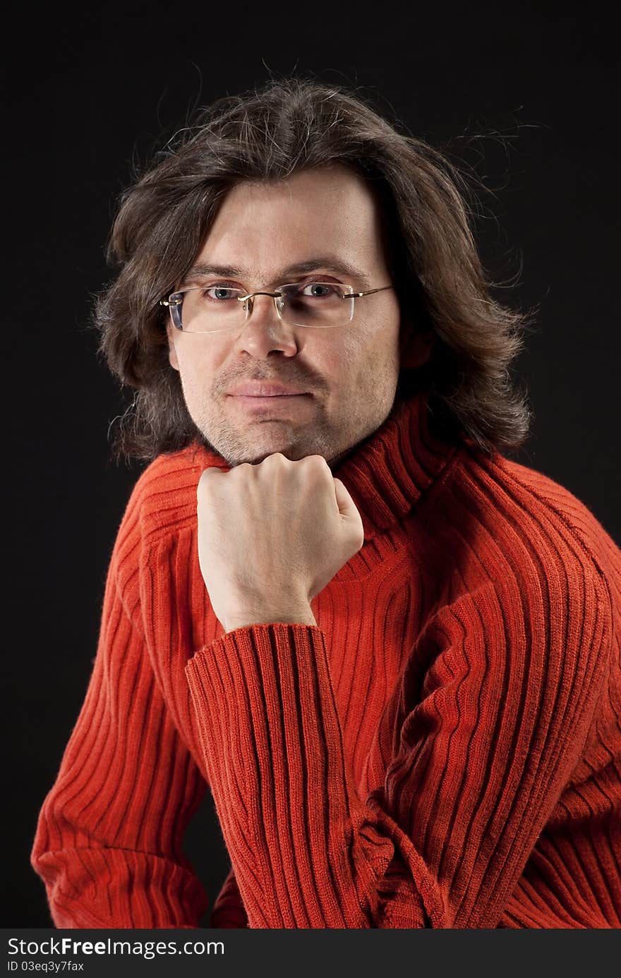 Man with log hair in red sweater and glasses.