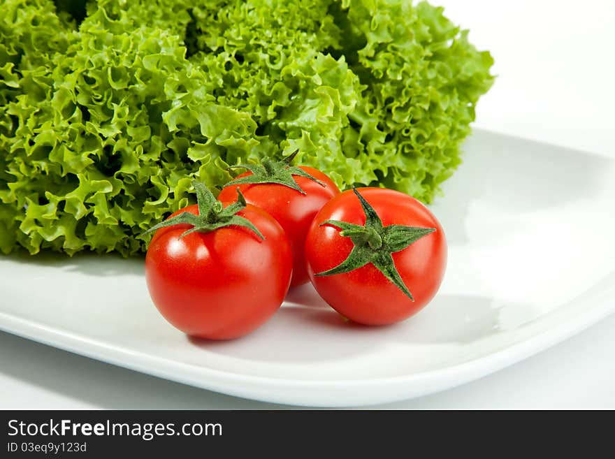 Three tomatos with salad in the background. Three tomatos with salad in the background