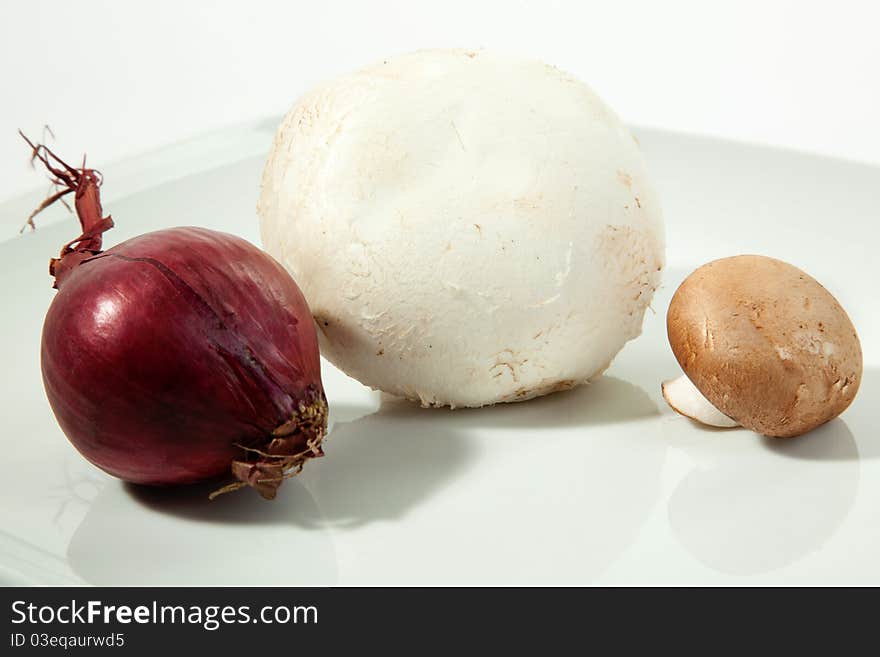 Two Mushrooms with a red onion on a plate.