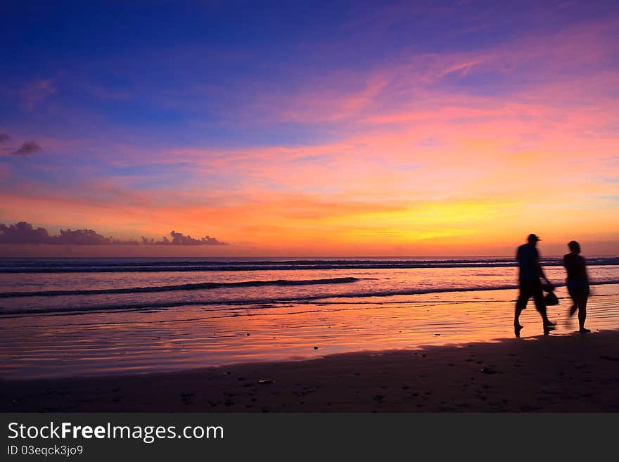 Female and male runners silhouette with a sunset sky and sea