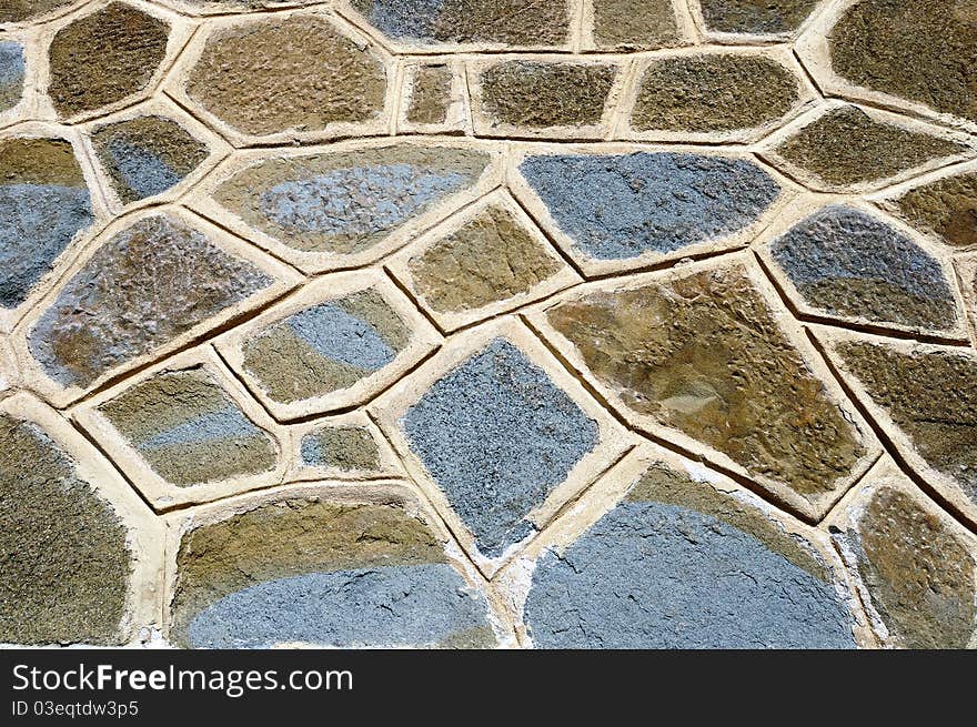 A rough wall made of colored cemented stones. A rough wall made of colored cemented stones