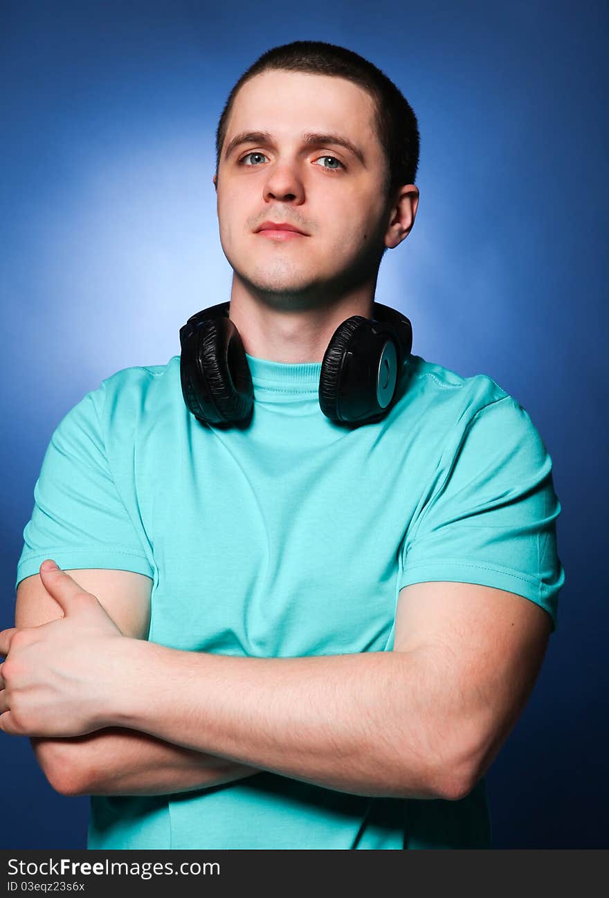 Man with headphones listening music at blue background