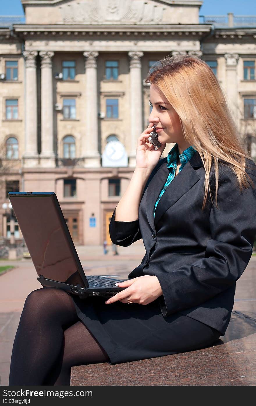 The business woman with a notebook speaks by phone against an old building. The business woman with a notebook speaks by phone against an old building