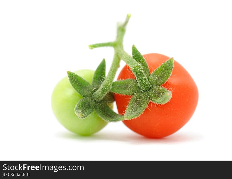 A green and a red cherry tomatoes isolated on a white background. A green and a red cherry tomatoes isolated on a white background