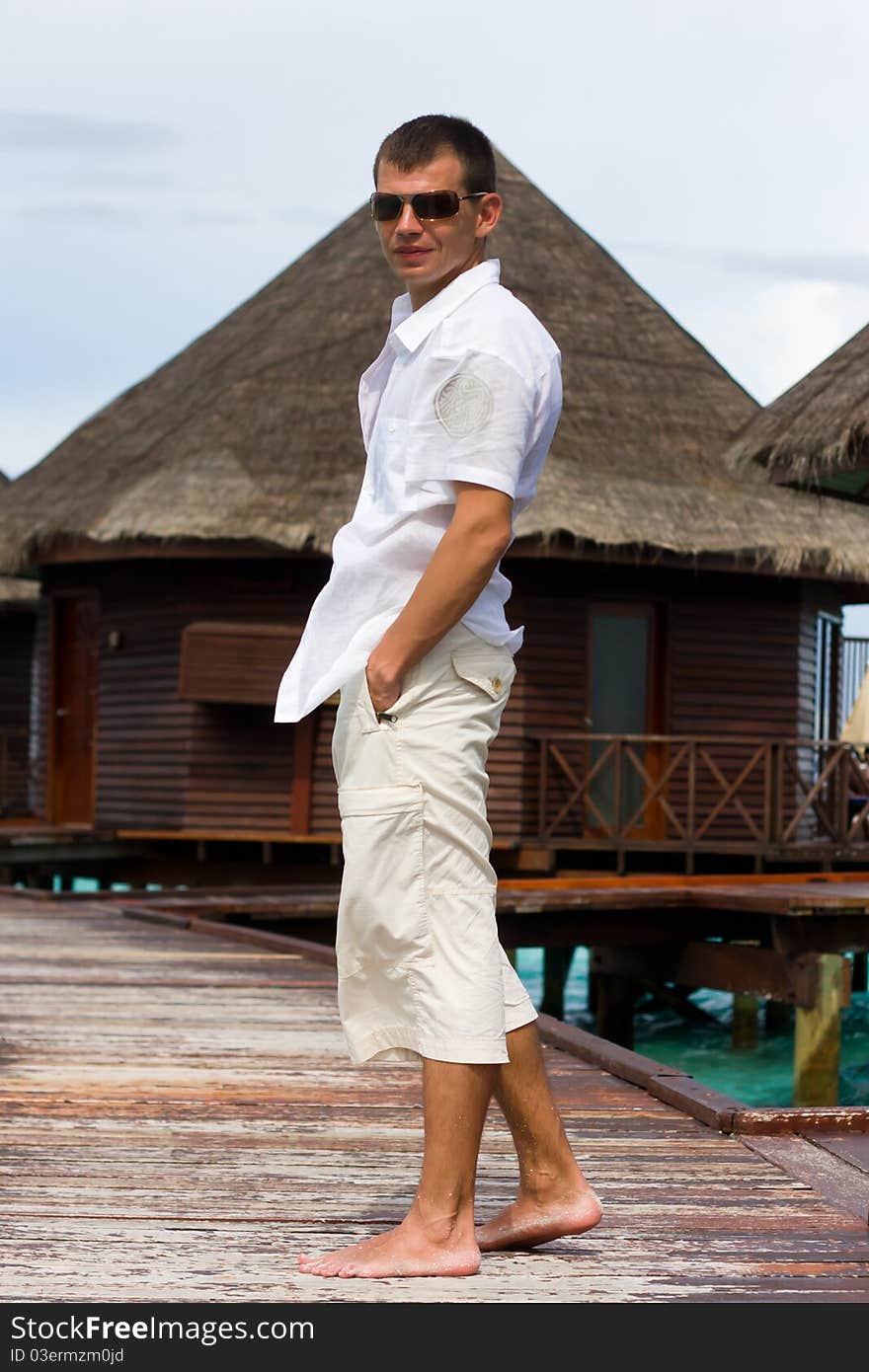 Man is in white on a pier. Man is in white on a pier